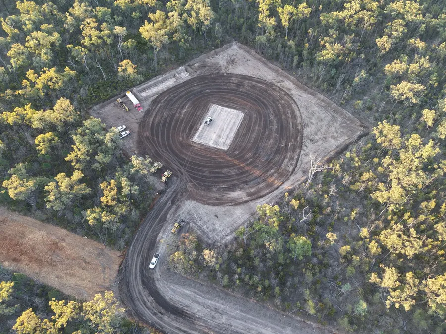 Aerial view of a large cleared pad in the bush with plant and trucks on site